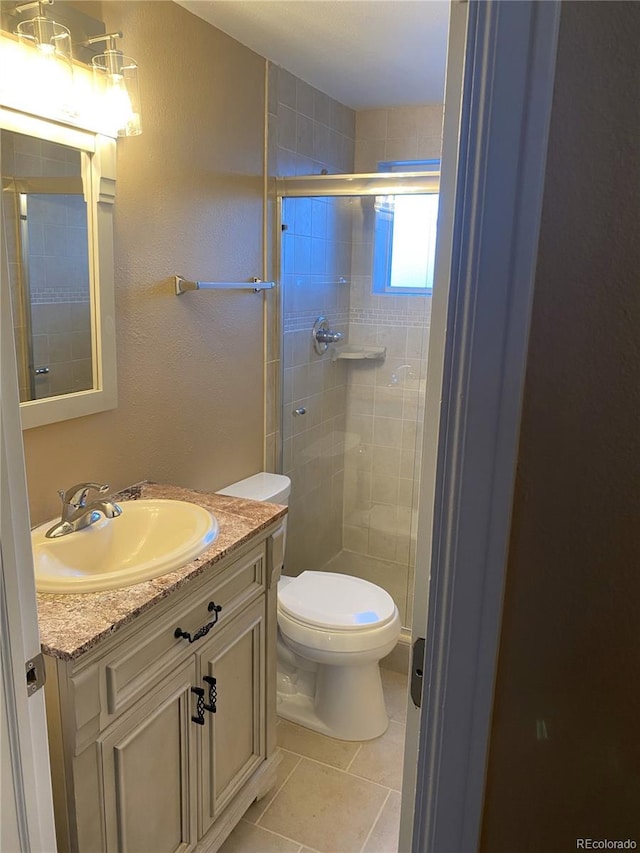 bathroom with a shower with door, tile patterned floors, toilet, and vanity