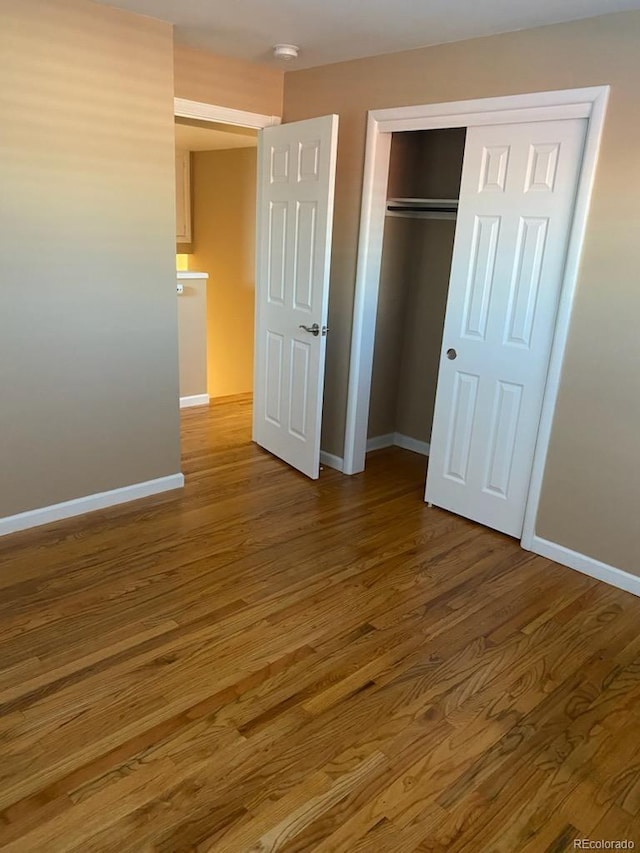 unfurnished bedroom with a closet and hardwood / wood-style flooring