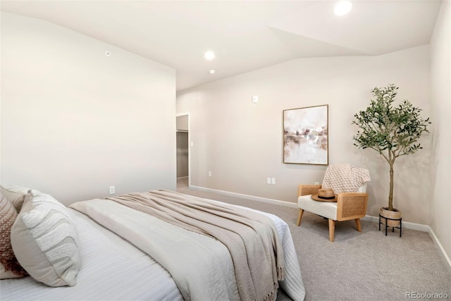 carpeted bedroom with a walk in closet and vaulted ceiling