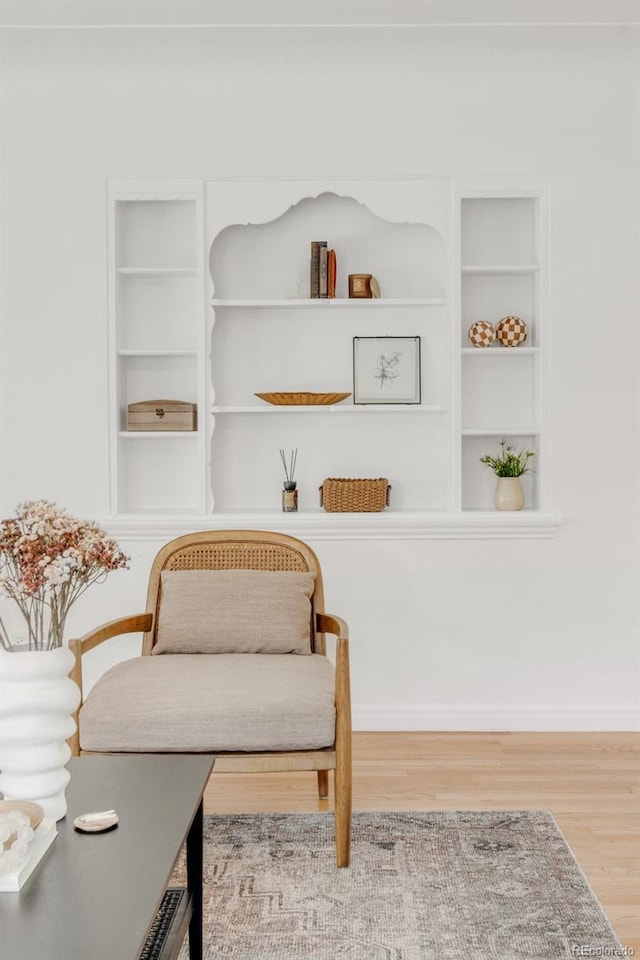 sitting room with hardwood / wood-style floors and built in shelves