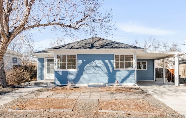 view of front of house featuring driveway, a carport, a shingled roof, and fence