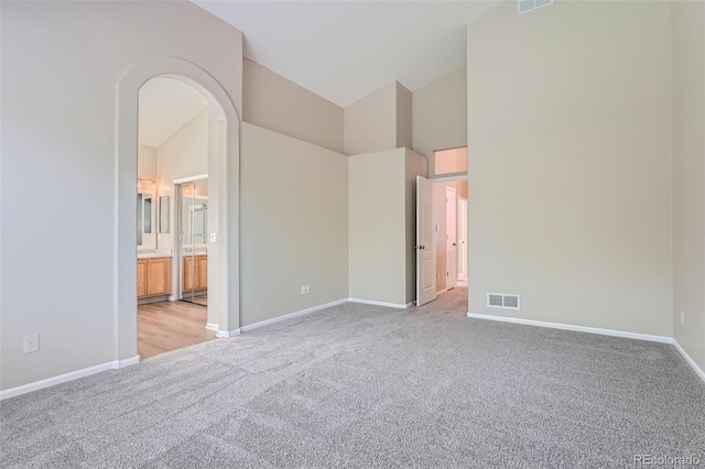 22436 E Maplewood Pl, Aurora, CO 80015 - unfurnished bedroom with light carpet, high vaulted ceiling, arched walkways, and ensuite bathroom