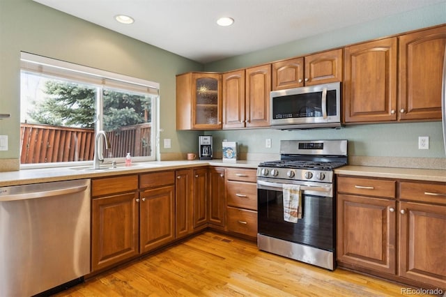 kitchen featuring stainless steel appliances, sink, and light wood-type flooring