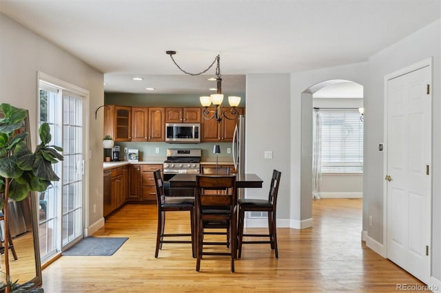 kitchen with appliances with stainless steel finishes, a chandelier, hanging light fixtures, and light hardwood / wood-style flooring