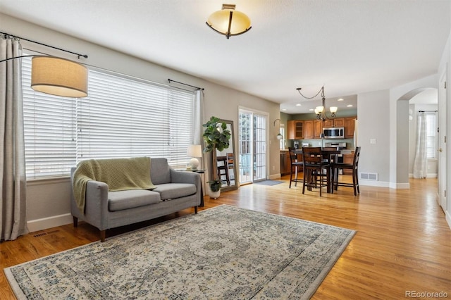 living room featuring plenty of natural light, a chandelier, and light hardwood / wood-style floors