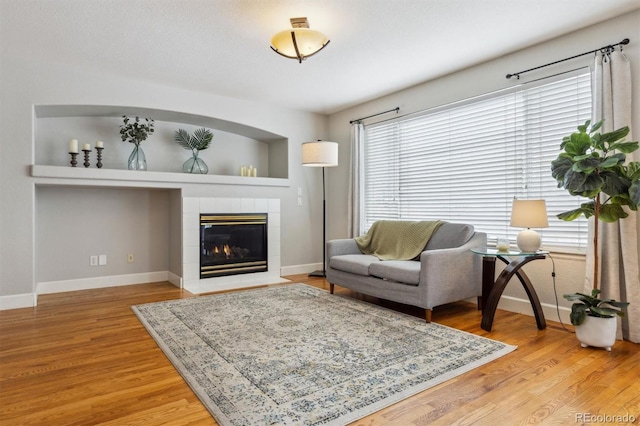 living room featuring wood-type flooring, built in features, and a fireplace