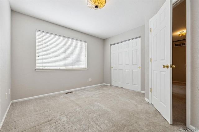 unfurnished bedroom featuring light colored carpet and a closet