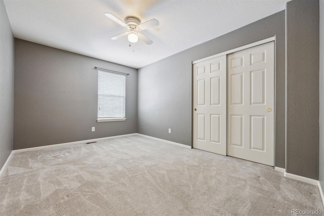 unfurnished bedroom with light colored carpet, a closet, and ceiling fan