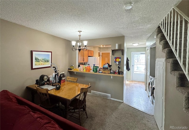 dining room featuring separate washer and dryer, a chandelier, a textured ceiling, visible vents, and carpet