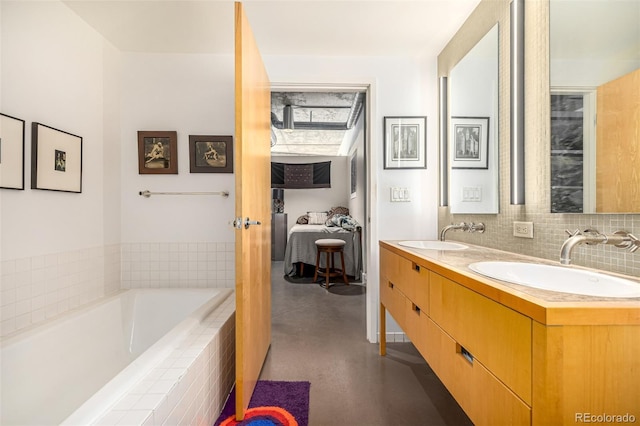 bathroom featuring a bath, decorative backsplash, double vanity, and a sink