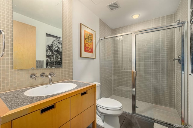 bathroom with vanity, toilet, visible vents, and a stall shower