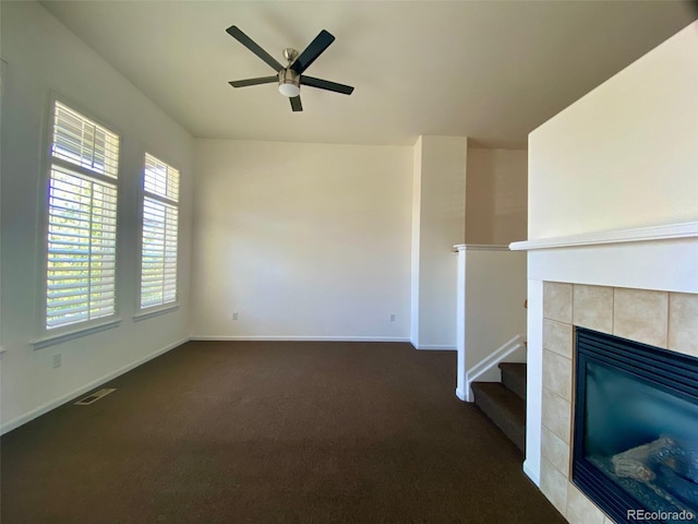 unfurnished living room with carpet, a tiled fireplace, and ceiling fan