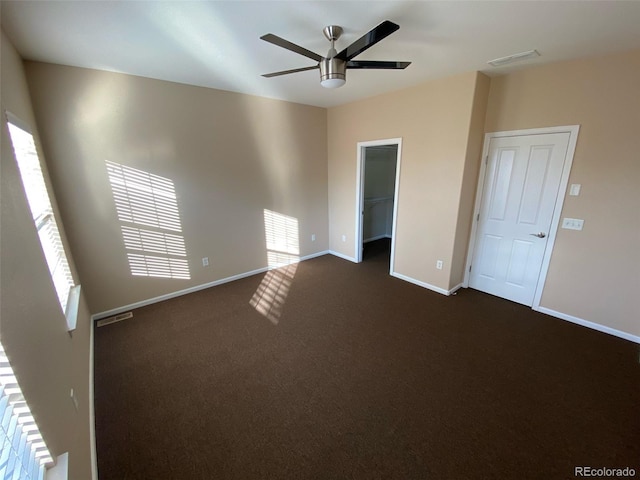 interior space featuring ceiling fan, a closet, carpet, and a walk in closet