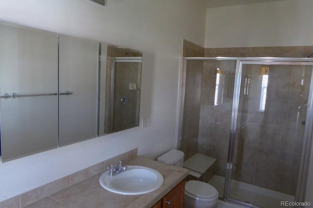 bathroom with a shower with door, toilet, and vanity