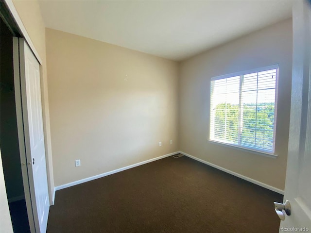 unfurnished bedroom featuring a closet and dark carpet