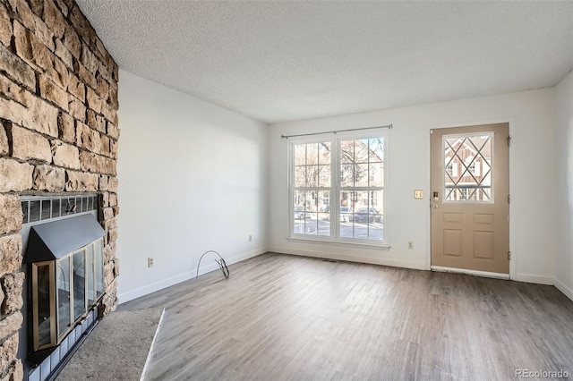 unfurnished living room with a fireplace, a textured ceiling, and light wood-type flooring