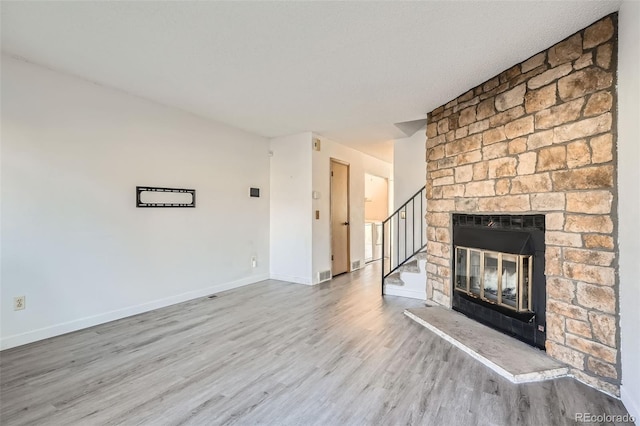 unfurnished living room featuring a stone fireplace and light hardwood / wood-style flooring