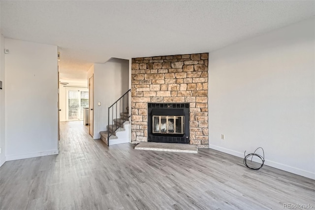 unfurnished living room featuring a large fireplace, light hardwood / wood-style flooring, and a textured ceiling