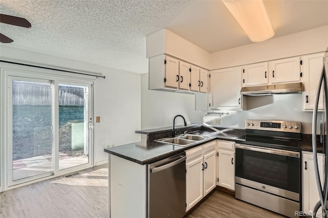 kitchen featuring sink, stainless steel appliances, kitchen peninsula, white cabinets, and light wood-type flooring