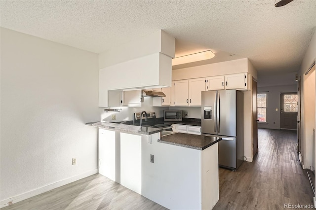 kitchen featuring white cabinets, light wood-type flooring, a textured ceiling, kitchen peninsula, and stainless steel appliances