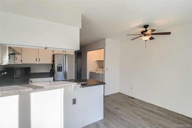 kitchen with hardwood / wood-style floors, ceiling fan, stainless steel fridge, independent washer and dryer, and a textured ceiling