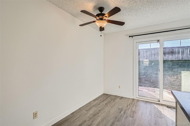 spare room with ceiling fan, a textured ceiling, and light wood-type flooring