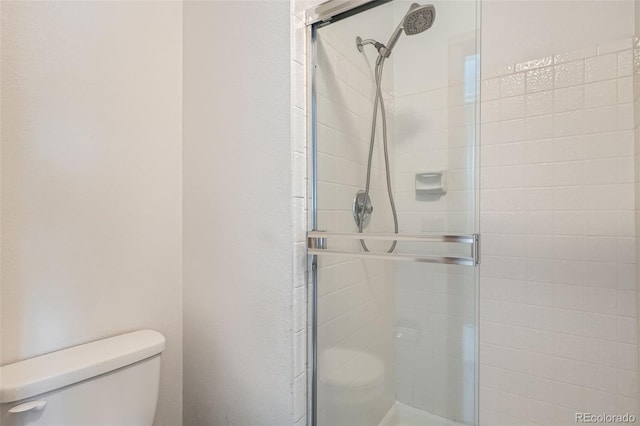 bathroom with toilet and a shower with shower door