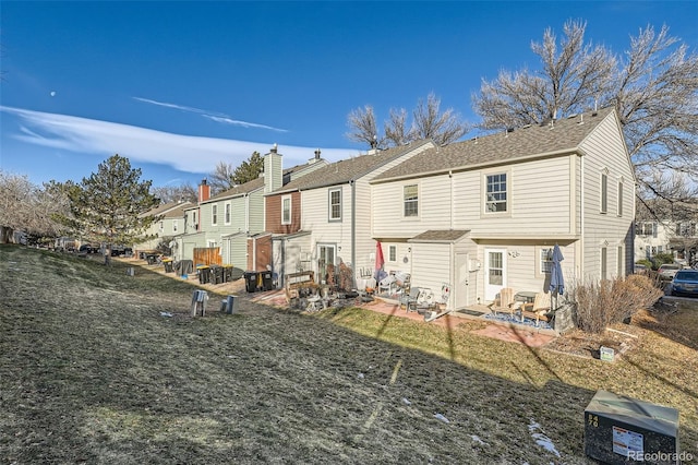 back of property with a yard and a patio