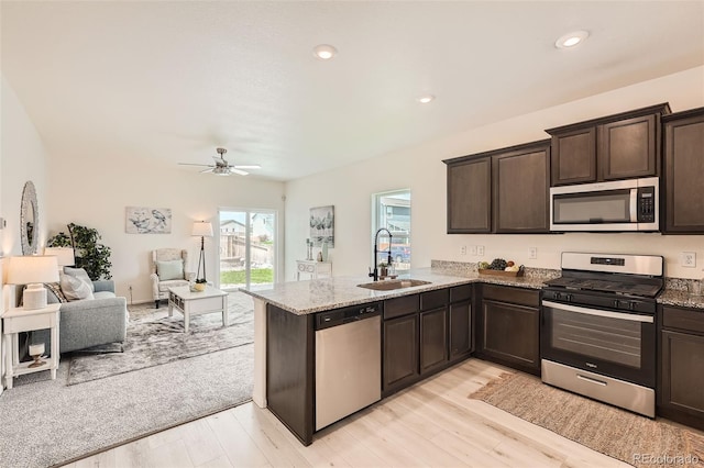401 Quincy Rr Ave, Keenesburg, CO 80643 - kitchen with appliances with stainless steel finishes, a sink, open floor plan, dark brown cabinetry, and light stone counters