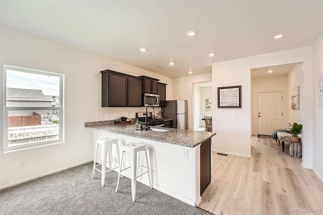 401 Quincy Rr Ave, Keenesburg, CO 80643 - kitchen with appliances with stainless steel finishes, dark brown cabinets, a kitchen bar, a sink, and recessed lighting