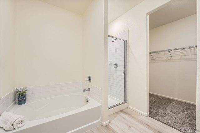 401 Quincy Rr Ave, Keenesburg, CO 80643 - full bathroom with a garden tub, a stall shower, a walk in closet, wood finished floors, and baseboards