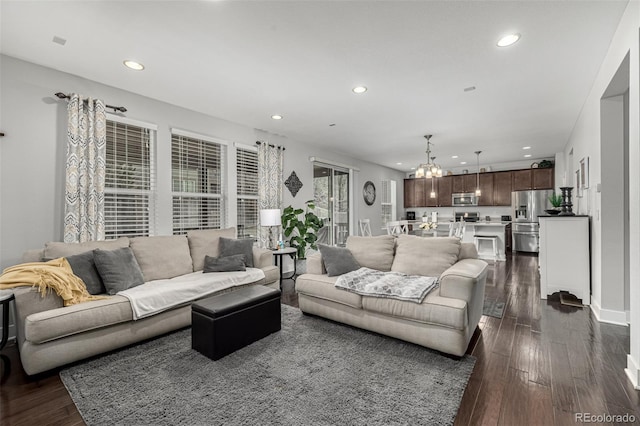 living area featuring dark wood-type flooring, recessed lighting, baseboards, and an inviting chandelier