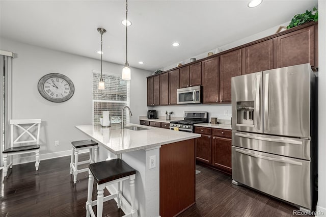 kitchen with dark brown cabinetry, light stone counters, appliances with stainless steel finishes, pendant lighting, and a sink