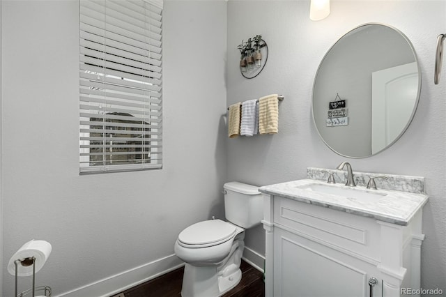 bathroom featuring toilet, wood finished floors, vanity, and baseboards