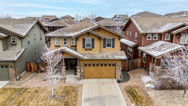 view of front of home featuring driveway, a garage, stone siding, a residential view, and fence