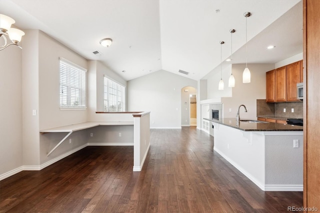 kitchen featuring lofted ceiling, sink, decorative light fixtures, a kitchen breakfast bar, and dark hardwood / wood-style flooring