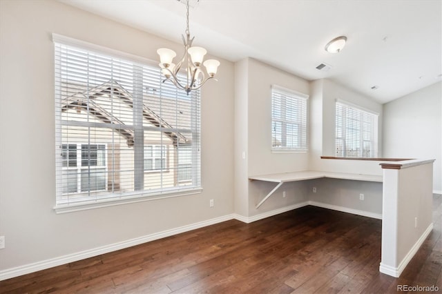 unfurnished dining area featuring a chandelier, dark wood-type flooring, visible vents, baseboards, and built in desk