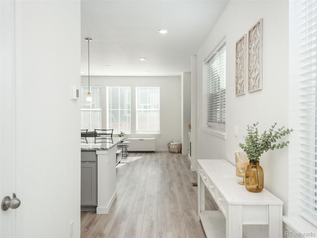 hallway with radiator heating unit and light hardwood / wood-style flooring