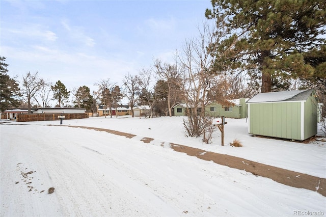 yard layered in snow featuring a storage unit