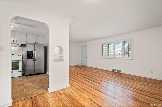 kitchen with stainless steel refrigerator with ice dispenser, range, white cabinets, and light wood-type flooring