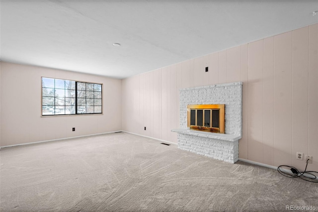 unfurnished living room featuring light carpet, wooden walls, and a brick fireplace