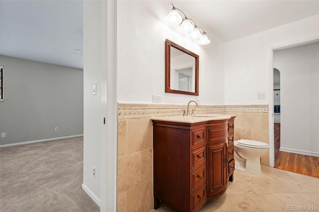 bathroom featuring toilet, vanity, tile patterned floors, and tile walls