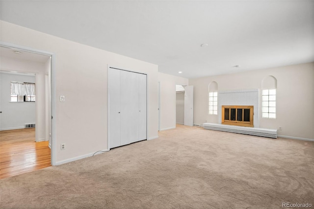 unfurnished living room featuring light colored carpet and baseboard heating