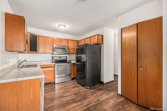 kitchen with dark wood-type flooring, stainless steel appliances, sink, and a textured ceiling