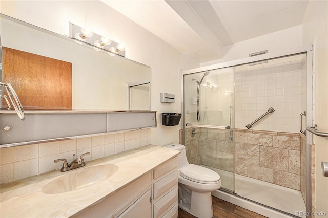 bathroom with hardwood / wood-style flooring, vanity, decorative backsplash, a shower with shower door, and toilet