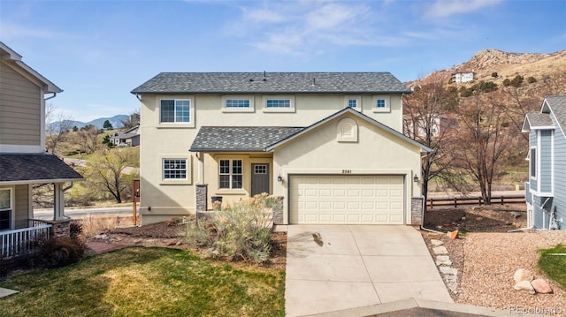 2541 Hot Springs Ct, Colorado Springs, CO 80919 - traditional-style home featuring driveway, a shingled roof, an attached garage, a mountain view, and stucco siding