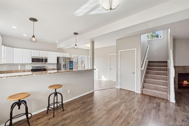 2541 Hot Springs Ct, Colorado Springs, CO 80919 - kitchen featuring a kitchen bar, wood finished floors, a healthy amount of sunlight, and appliances with stainless steel finishes