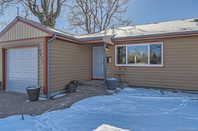 snow covered property entrance featuring a garage