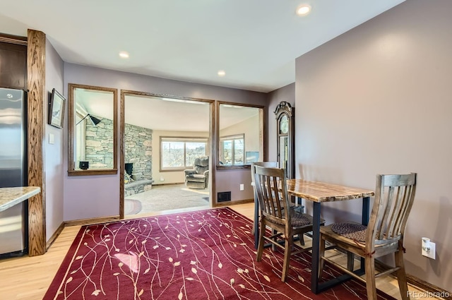 dining room with wood-type flooring and a stone fireplace