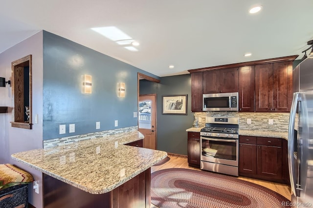 kitchen featuring stainless steel appliances, tasteful backsplash, a breakfast bar, and kitchen peninsula